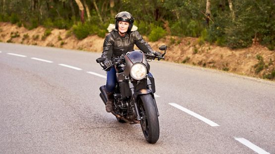Motocycliste chevauchant une moto d’allure futuriste sur une route déserte.